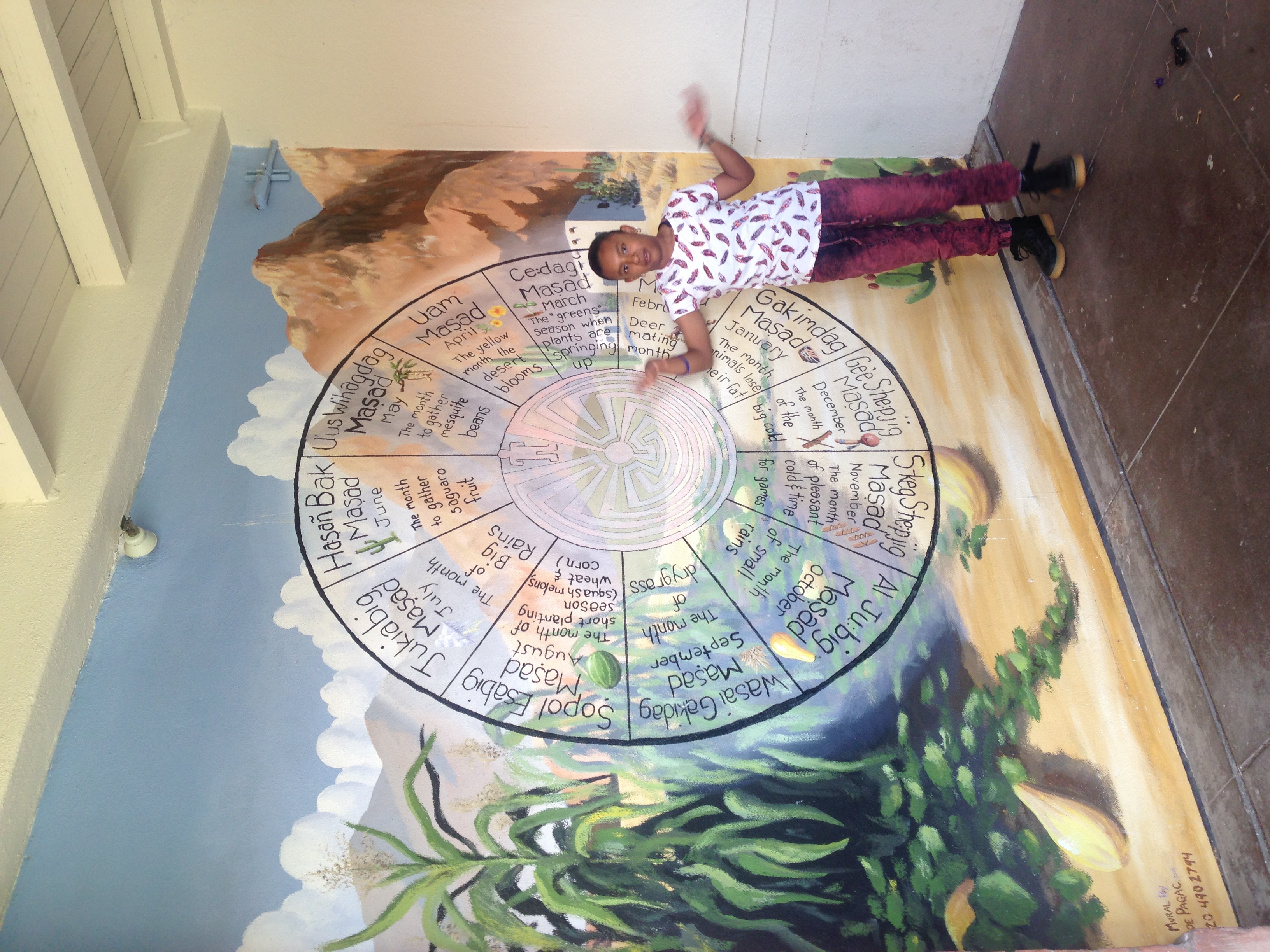 Tohono O'Odham calendar wheel mural at Manzo Elementary School showing seasonal native and cultivated foods, with student explaining mural during tour